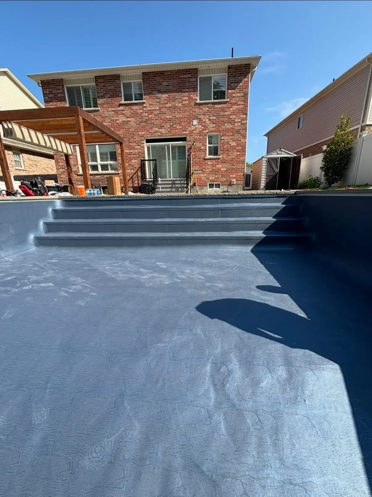 New dark grey pool liner laid inside an empty pool shell showing steps