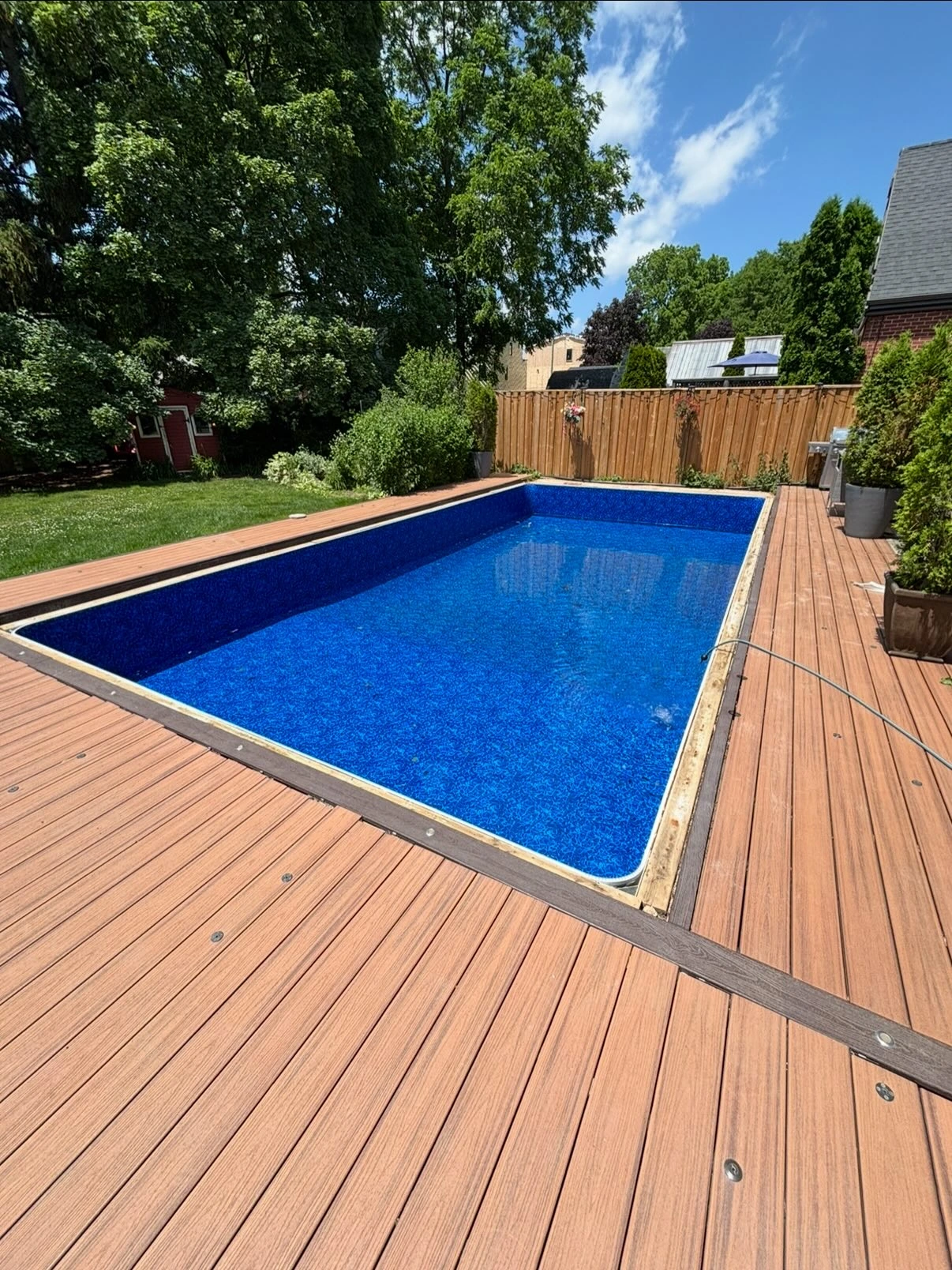 Rectangular pool with a new dark blue liner surrounded by a wooden deck